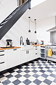 Open-plan kitchen with chequered floor below staircase