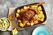Roast chicken with potatoes and lemons in a baking tin (seen from above)