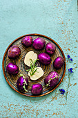 Purple potatoes with thyme and rosemary on a blue old table