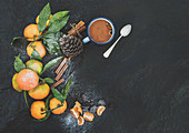 Mandarinen mit Blättern, Zimtstangen, Vanille, Pinienzapfen und Becher heiße Schokolade