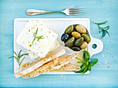 Fresh feta cheese with olives, basil, rosemary and bread slices