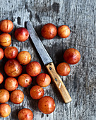 Wild plums (ringlovs) with a knife on a wooden surface
