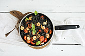 Schwarze Spaghetti mit Garnelen, Tomaten und Pesto in Pfanne