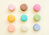 Sweet colorful French macaroon biscuits on pastel yellow background, top view