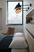 Drei Wandleuchten und Nischenregal über Doppelbett, Designerstuhl vor Fenster im Schlafzimmer