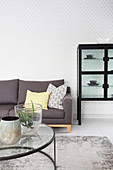Graues Sofa, Couchtisch mit Glasplatte und Vitrinenschrank im Wohnzimmer