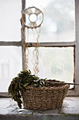 Basket of herbs on windowsill below dreamcatcher