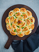 Pull-apart bread filled with ham and cheese on a wooden board (seen from above)