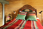 Doppelbett mit Ethno Accessoires im Schlafzimmer mit Holzverkleidung