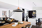 Black and white fitted kitchen, long dining table and lounge with upholstered sofa in an open living area