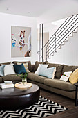 Upholstered suite with cushions and leather coffee table in front of staircase wall