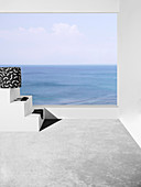 Pouf with black and white cover and bikini on terrace with sea view