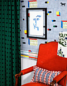 Roter Sessel vor Designertapete und Zeichnung in schwarzem Rahmen