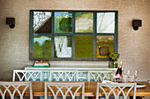 Dining table with chairs, sideboard behind and patchwork picture on wallpapered wall