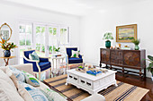Living room with antique sideboard, blue upholstered armchairs and white coffee table