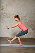 A young woman performing a one-legged knee bend