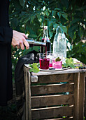 A woman preparing a refreshing drink with blackcurrant syrup