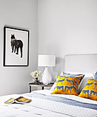 Cushions with zebra motif on double bed and side table with table lamp in bright bedroom