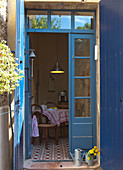 Blick durch geöffnete Terrassentür mit blau lackiertem Rahmen in Wohnküche