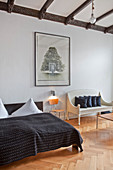 Chair and white bench next to double bed with black bedspread in bedroom