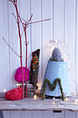 Creative wintry arrangement of natural materials, fairy lights and zinc bucket