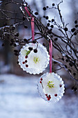 Handmade ice pendants with hellebore flowers and berries frozen inside