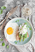 Breakfast toast with asparagus, grated parmesan and fresh basil, served with fried egg