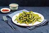 Plate of stir fried green beans with sesame seeds on a blue background