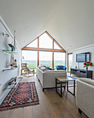 Pale seating and glass shelves in elegant living room with glass wall