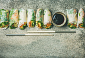 Vegan spring or summer rice paper rolls with vegetables, sauce and chopsticks