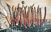 Purple asparagus in row over rustic wooden background