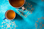 Koriander-Ingwer-Tee in Metalltassen auf azurblauem Untergrund