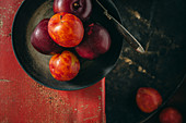 Various different coloured plums in a black pan