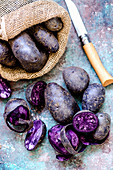 Violette Kartoffeln im Jutesack und davor