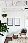 Armchair, sideboard and houseplants in living room with white wooden panelling