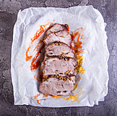 Slices of baked roasted pork meat on parchment with mustard and ketchup