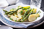 Boiled potato with grilled green asparagus on blue plate