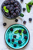 Blackberry harvest in an iron mug and a saucer on a concrete background