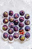 Twenty-one whole fig fruit and one cut in individual packing on a concrete background