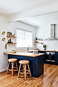 Wicker stools at counter in open-plan kitchen with wooden floor
