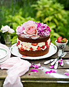 Strawberry cake with cream and roses on a garden table