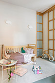 Bed and balance bike in child's bedroom in pastel shades