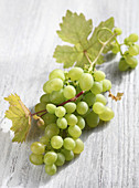 Green grapes on a wooden background with vine leaves