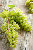 Green grapes on a wooden background with vine leaves