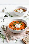 A bowl of roasted tomato soup topped with fresh basil, ricotta and toasted seeds