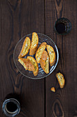 Italian almond biscotti called Cantuccini on a plate, served with a coffe on a wooden table