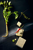 Food art: tofu with coriander, chilli and pepper on a black surface