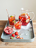 Pomegranate Pimms in jug with fruit on metal tray