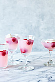 Pink lemonade jelly with raspberries and cream on light marble background