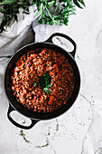 A bolognese sauce in a pan on a marble background